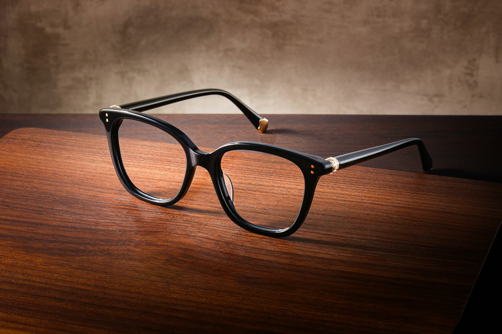 Black acetate eyeglasses on a warm wood surface